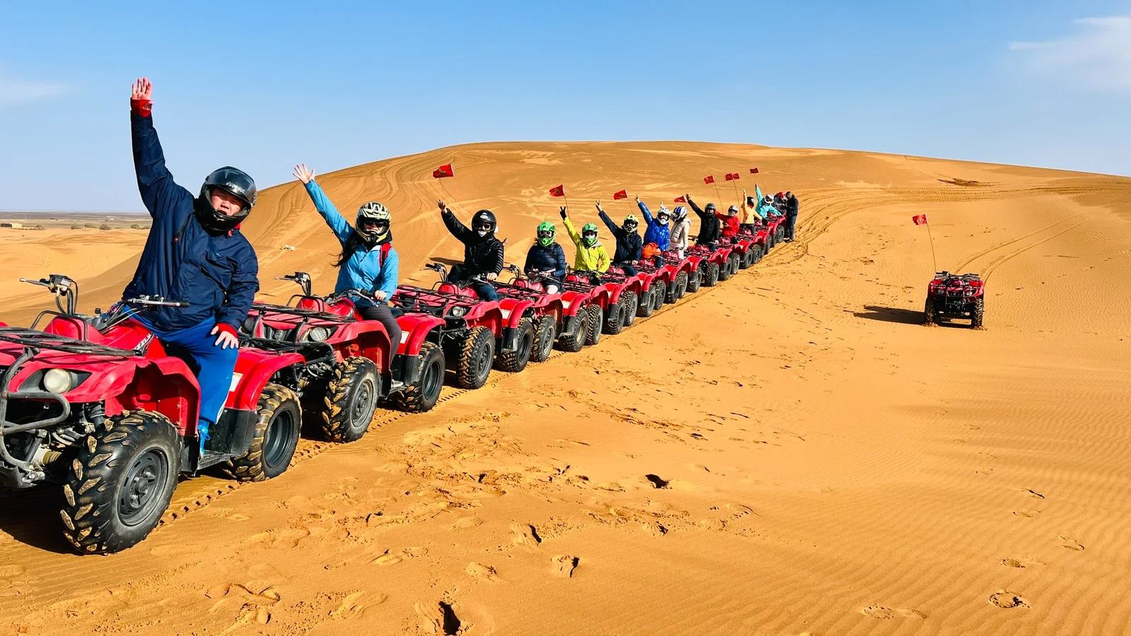 OnTheGo team riding red ATVs in a line through the desert on a 2023 group trip in Morocco
